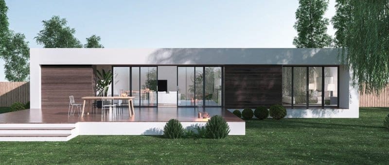 Spacious white flat with wooden floor and stairs, glass windows and doors. Sorrounded by trees, plants, and grass. With TV, sofa and bed inside the flat. Have a wooden table outside with five steel chairs.